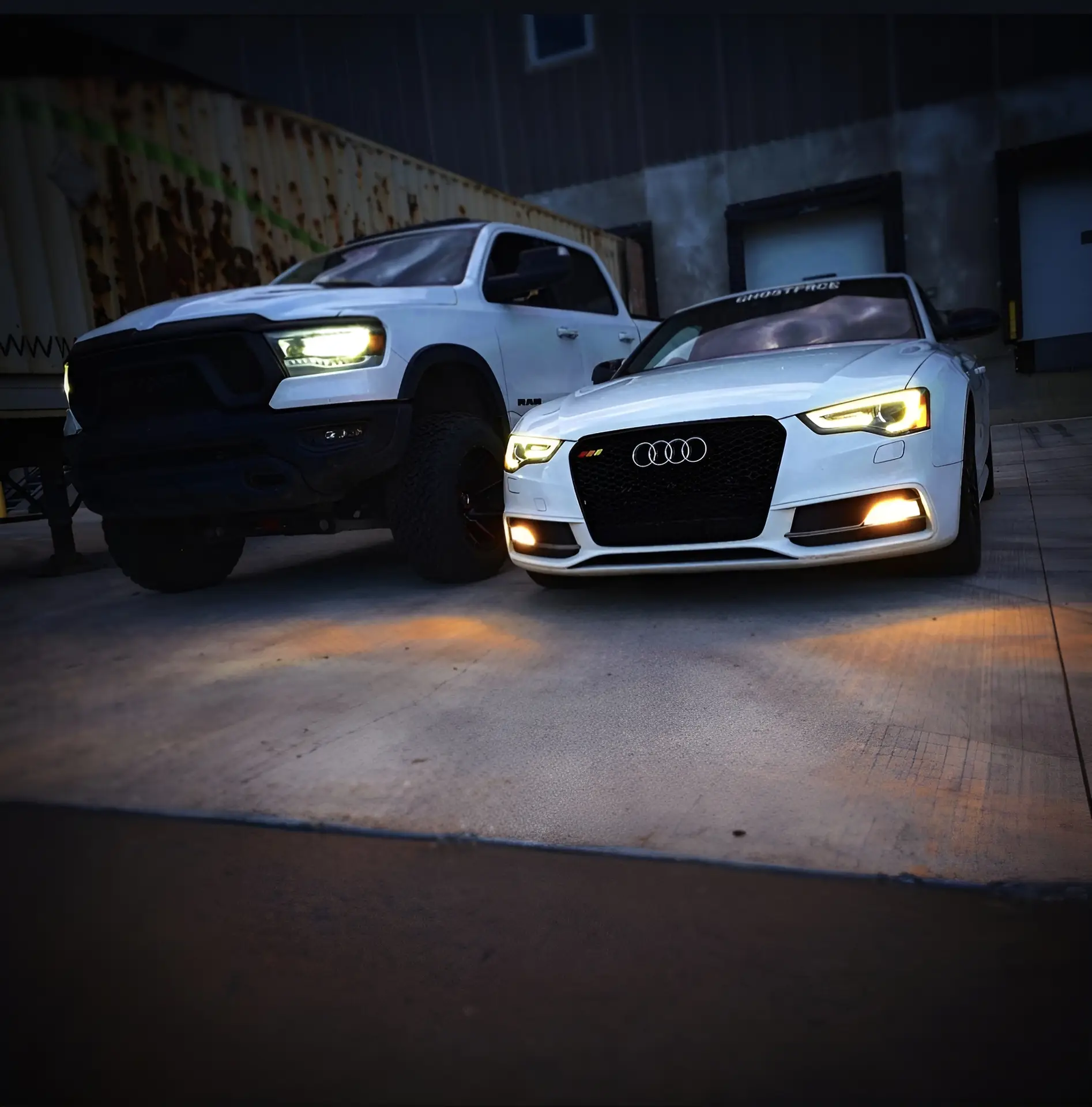White Audi S5 next to a white Ram truck.